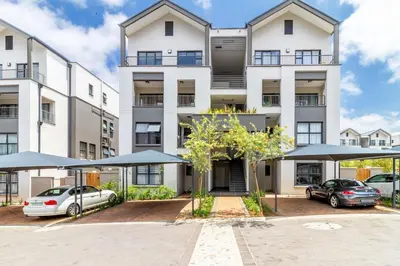 an apartment building with umbrellas in a parking lot at AlimamaSpaces The Munyakas Manson 1543 in Midrand