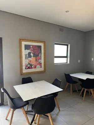 a room with two tables and chairs and a picture on the wall at Glow Events &Guest House in Centurion