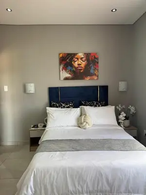 a bedroom with a large bed with a painting on the wall at Glow Events &Guest House in Centurion