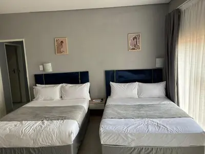 two beds sitting next to each other in a room at Glow Events & Guest House in Centurion