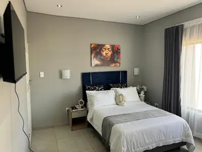 a bedroom with a bed and a painting on the wall at Glow Events & Guest House in Centurion