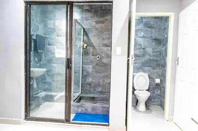 a shower stall in a bathroom with a toilet at Glow Events & Guest House in Centurion
