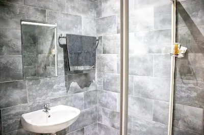 a gray tiled bathroom with a sink and a mirror at Glowti Event & Guest House in Centurion