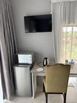 a desk with a computer and a chair next to a window at Glowti Event & Guest House in Centurion