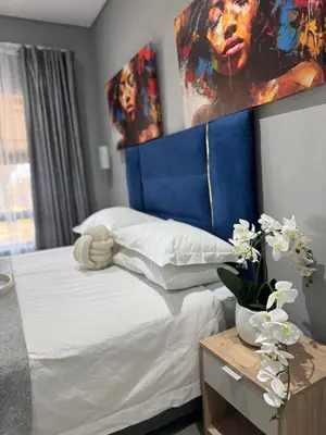 a bedroom with a bed with a blue headboard at Glowti Event & Guest House in Centurion