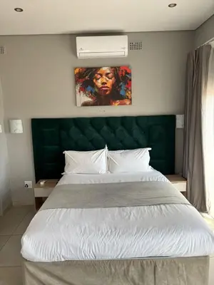 a bedroom with a large bed with a green headboard at Glowti Event & Guest House in Centurion