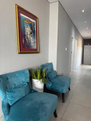 a living room with a blue couch and a chair at Glowti Event & Guest House in Centurion
