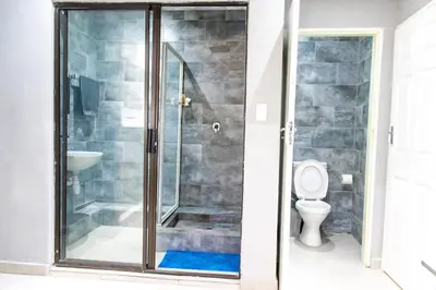 a shower stall in a bathroom with a toilet at Glowti Event & Guest House in Centurion