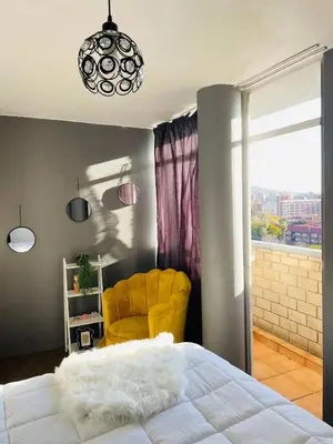 a bedroom with a white bed and a yellow chair at Sunnyside hidden gem in Pretoria