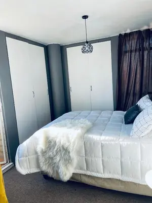 a bedroom with a white bed with three windows at Sunnyside hidden gem in Pretoria