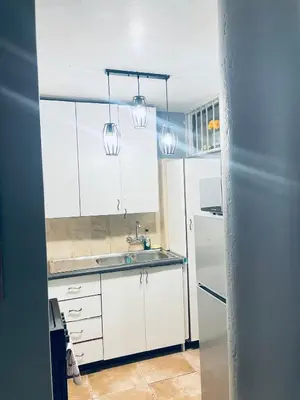 a kitchen with white cabinets and a sink and two lights at Sunnyside hidden gem in Pretoria
