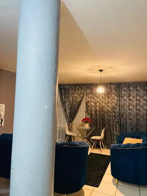 a room with blue chairs and a table and a column at Sunnyside hidden gem in Pretoria