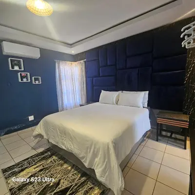 a bedroom with a large bed with a blue wall at Yello Guest House and Spa in Louis Trichardt