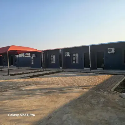 a blue building with a red canopy in a parking lot at Yello Guest House and Spa in Louis Trichardt