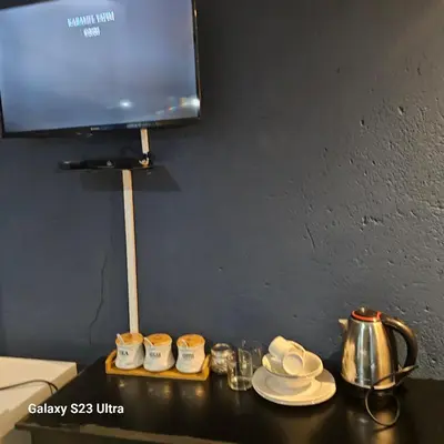 a table with cups and saucers and a tv at Yello Guest House and Spa in Louis Trichardt
