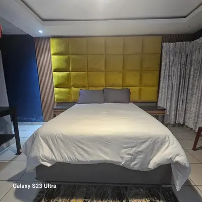 a bedroom with a large bed with a yellow headboard at Yello Guest House and Spa in Louis Trichardt