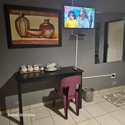 a table with a chair and a tv in a room at Yello Guest House and Spa in Louis Trichardt