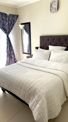a bedroom with a large white bed and a window at Prospect Guest House in Pretoria