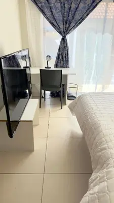 a bedroom with a bed and a desk and a window at Prospect Guest House in Pretoria