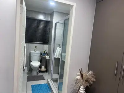 a bathroom with a toilet and a glass shower at Private Space in a House in Pretoria