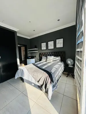 a bedroom with a large bed with black walls at Enawe Lodge in Erasmus