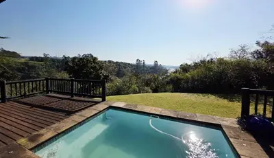 a swimming pool with a deck next to a yard at Bush Willow Lodge in Hazyview