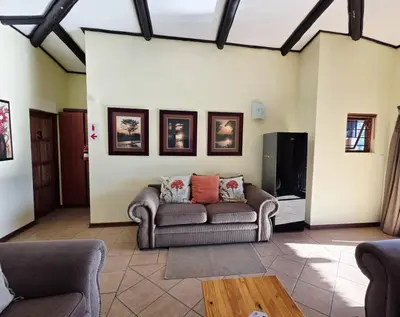 a living room with a couch and a tv at Bush Willow Lodge in Hazyview
