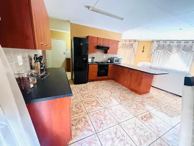 a kitchen with a black refrigerator and a tile floor at Secure Home on Fuchs in Polokwane