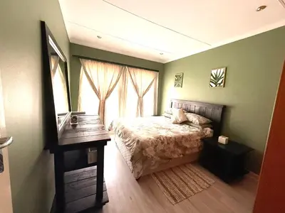 a bedroom with a bed with a table and a mirror at Secure Home on Fuchs in Polokwane