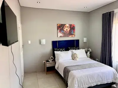 a bedroom with a bed and a painting on the wall at Glowti Events & Guest House in Centurion