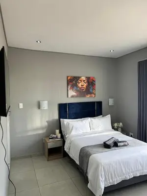 a bedroom with a large white bed and a painting on the wall at Glowti Events & Guest House in Centurion