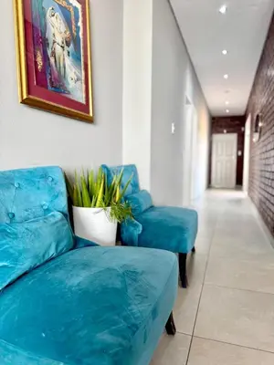 a living room with two blue chairs and a couch at Glowti Events & Guest House in Centurion
