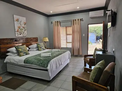 a bedroom with a bed and a chair and a window at 4 Trees Accommodation in Polokwane