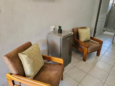 a living room with two chairs and a refrigerator at 4 Trees Accommodation in Polokwane