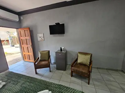 a room with two chairs and a television on a wall at 4 Trees Accommodation in Polokwane