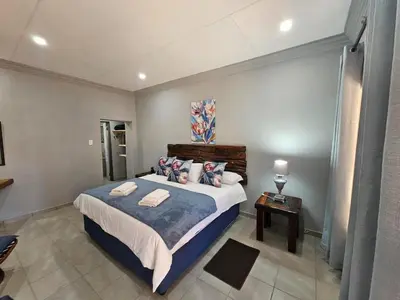 a bedroom with a bed with a blue blanket and pillows at 4 Trees Accommodation in Polokwane