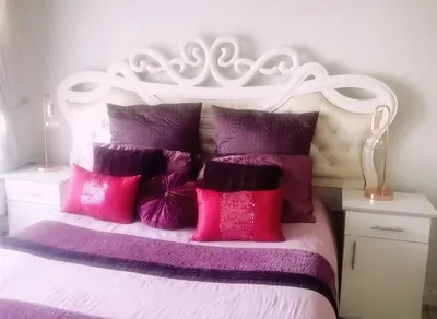 a bed with pink and purple pillows on it at Queens at The Blyde Lagoon in Pretoria