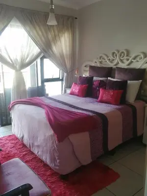 a bedroom with a large bed with pink pillows at Queens at The Blyde Lagoon in Pretoria