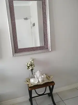 a mirror on a wall above a table with flowers at Queens at The Blyde Lagoon in Pretoria