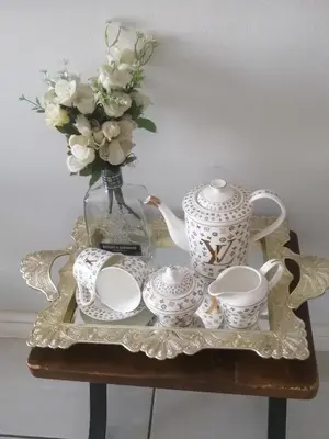 a table with a vase of flowers and a tea set at Queens at The Blyde Lagoon in Pretoria