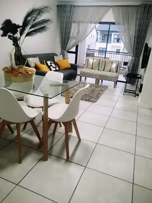 a living room with a glass table and chairs at Queens at The Blyde Lagoon in Pretoria