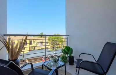 a room with chairs and a table and a balcony at GatesofGail Luxury Apartments in Midrand