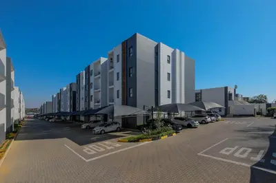 a large building with cars parked in a parking lot at GatesofGail Luxury Apartments in Midrand