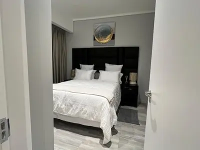 a bedroom with a large bed with white sheets and pillows at Continental Menlyn Maine Residence in Pretoria