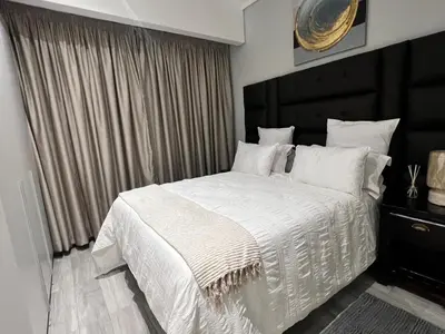 a bedroom with a white bed with a black headboard at Continental Menlyn Maine Residence in Pretoria