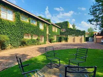 three chairs sitting in the grass in front of a building at Cairos Guest House in Witbank