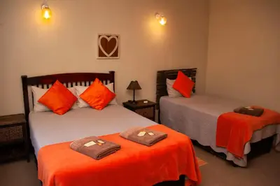 two beds in a room with orange and gray at Cairos Guest House in Witbank