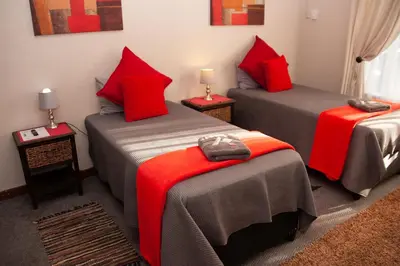 a room with two beds with red pillows at Cairos Guest House in Witbank