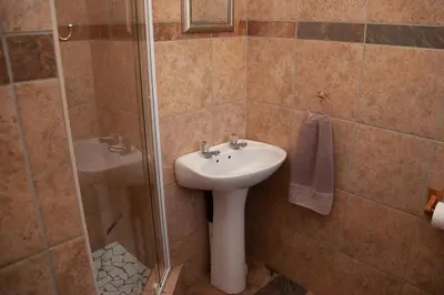 a bathroom with a sink and a shower at Cairos Guest House in Witbank