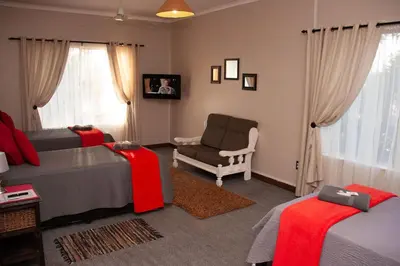 a bedroom with two beds and a chair and a couch at Cairos Guest House in Witbank